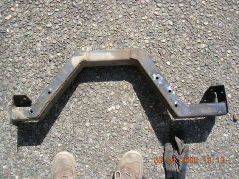 1995 Ford Bronco - This is a metal crossmember part, likely for a vehicle, shown on a gravel surface.