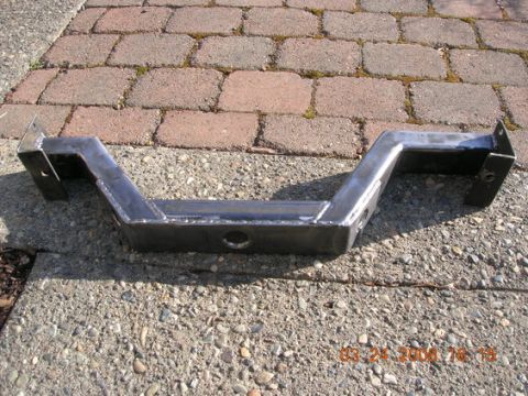 1995 Ford Bronco - A custom-fabricated metal crossmember is shown resting on a concrete surface with brick paving in the background.