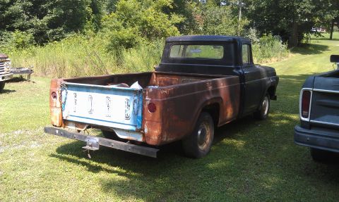 1957 Ford F-100 - A weathered 1957 Ford F-100 pickup truck sits in a grassy area next to another vehicle.