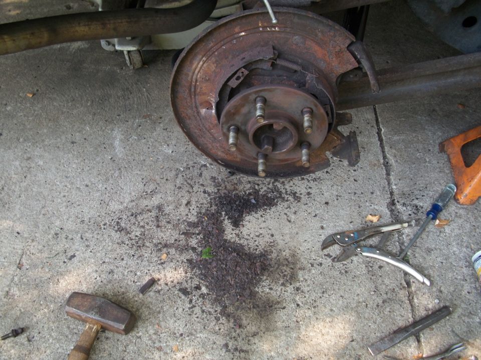 close-up of rusty rear brake assembly with tools on concrete