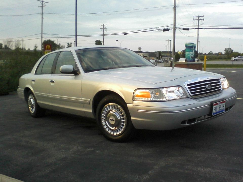 Silver 2001 Ford Crown Victoria sedan parked on asphalt, front 3/4 view, with chrome grille and hubcaps