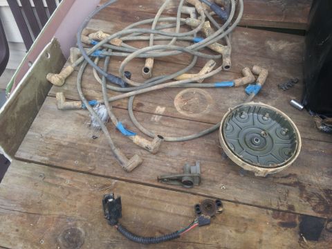 1988 Ford Bronco - Spark plug wires and distributor cap are laid out on a wooden surface.