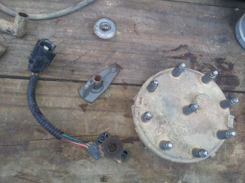 1988 Ford Bronco - Various engine ignition components are displayed on a weathered wooden surface, suggesting a repair or maintenance task.