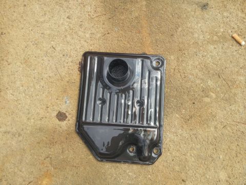 1988 Ford Bronco - A transmission filter pan is shown on a concrete surface, with a cigarette butt nearby.
