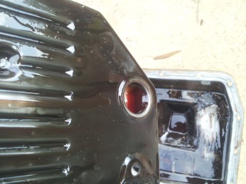 1988 Ford Bronco - Close-up of a transmission oil pan showing dark fluid and debris inside.