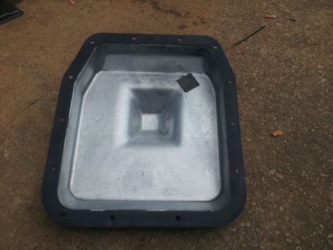 1988 Ford Bronco - A metal transmission oil pan with a black gasket is shown from above, resting on a concrete surface.