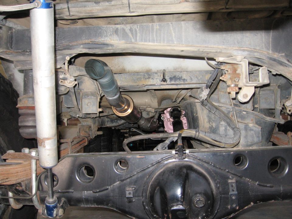 Underside view of a vehicle's rear axle and suspension with a custom exhaust pipe installed