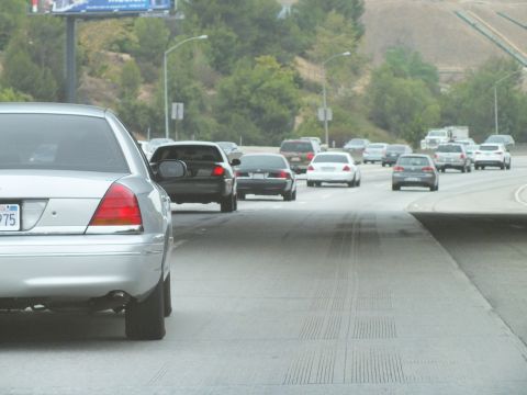 2003 Ford Crown Victoria - Photo of a silver Ford Crown Victoria on a freeway shoulder with cars driving by, not a technical document.