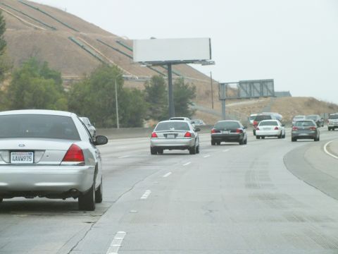 2003 Ford Crown Victoria - Photo of a silver Crown Victoria on a freeway shoulder with hills and a blank billboard, not a technical document.