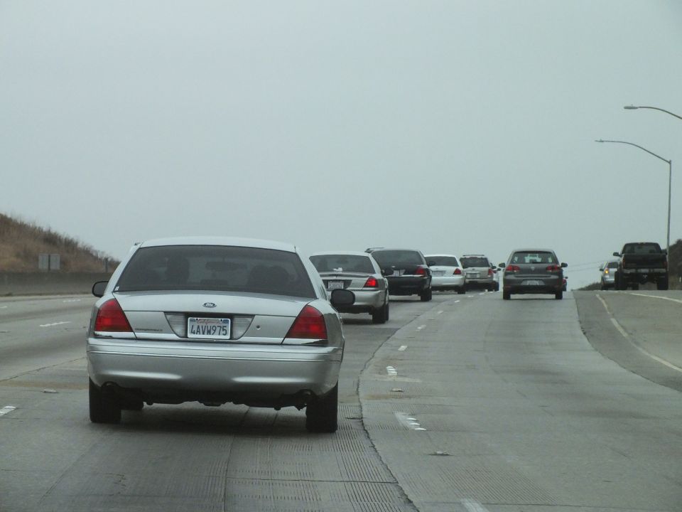 Silver Crown Victoria leading a line of cars on a hazy freeway