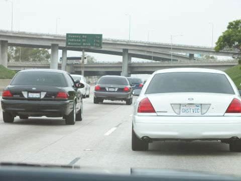 2003 Ford Crown Victoria - Photo of a white Crown Victoria in traffic near a freeway interchange with green exit signs, not a technical document.