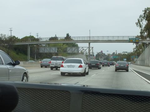 2003 Ford Crown Victoria - Photo of freeway traffic with a pedestrian bridge and Downey Rd sign, not a technical document.