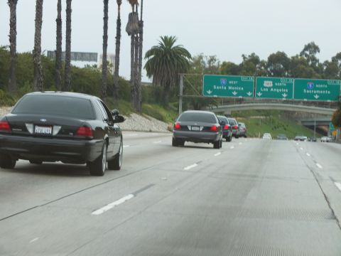 2003 Ford Crown Victoria - Black sedans travel a freeway approaching green overhead signs for Santa Monica, Los Angeles and Sacramento.
