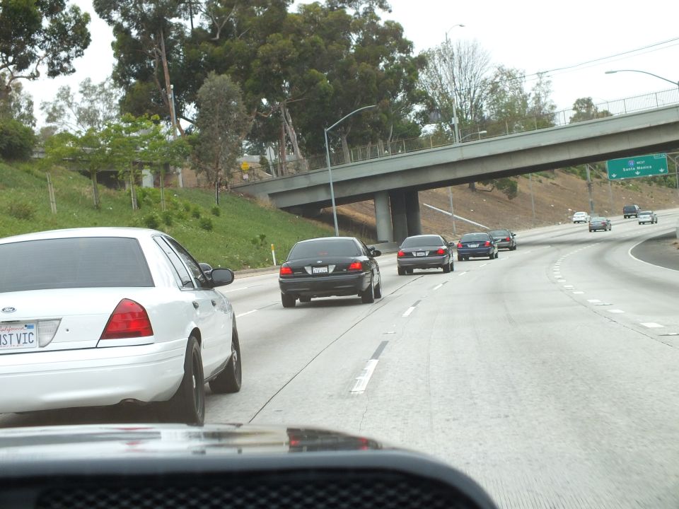 White Crown Victoria GHST VIC and sedans on curving freeway