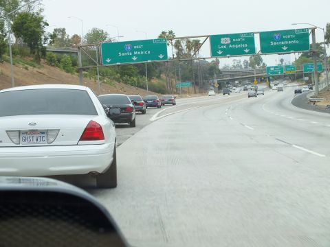 2003 Ford Crown Victoria - Photo of a white Crown Victoria on a freeway beneath overhead highway directional signs, not a technical document.