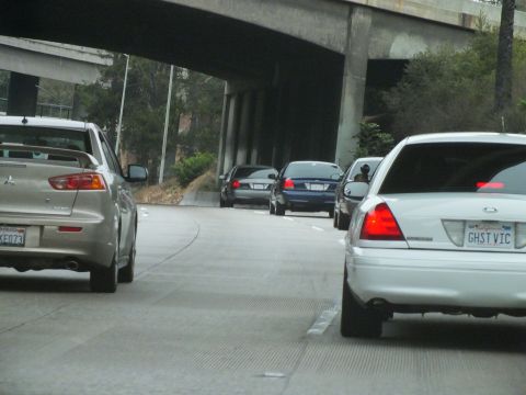 2003 Ford Crown Victoria - Photo of a white Crown Victoria and silver Mitsubishi on a freeway under a concrete overpass, not a technical document.