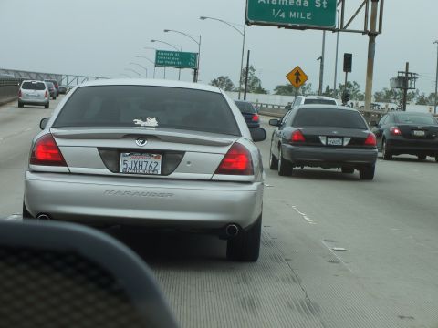 2003 Ford Crown Victoria - Photo of a silver Mercury Marauder in freeway traffic near an Alameda St sign, not a technical document.