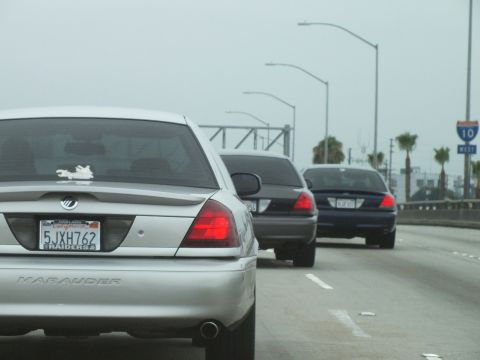 2003 Ford Crown Victoria - Photo of a silver Mercury Marauder and dark sedans on a hazy freeway, not a technical document.