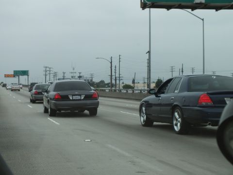2003 Ford Crown Victoria - Photo of a gray Crown Victoria and dark sedans driving on an overcast freeway, not a technical document.