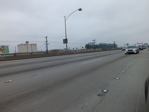 2003 Ford Crown Victoria - Photograph of an empty stretch of multilane freeway on an overcast day with roadside buildings and billboards.