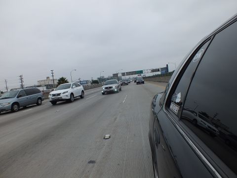 2003 Ford Crown Victoria - Photograph of freeway traffic on a gray day viewed past the side window of a dark sedan.