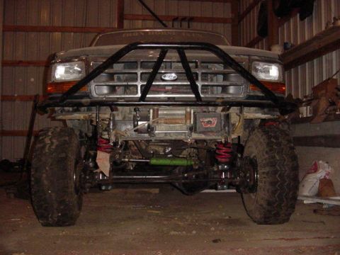 1992 Ford Bronco - This modified Ford truck features a prominent bull bar, winch, and lifted suspension, with large off-road tires.