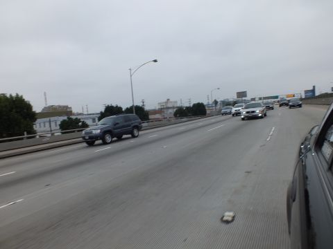 2003 Ford Crown Victoria - Photograph of freeway traffic including a dark SUV under an overcast sky.