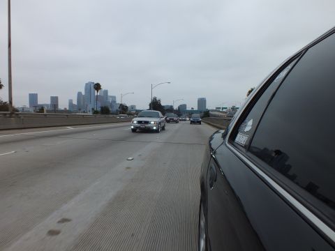 2003 Ford Crown Victoria - Photograph of a freeway approaching a downtown skyline, shot from a dark sedan.