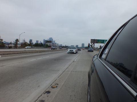 2003 Ford Crown Victoria - Photograph of freeway traffic with a distant skyline and overhead exit signs, taken from a dark sedan.