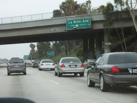 2003 Ford Crown Victoria - Photograph of freeway traffic passing under a green La Brea Ave overhead sign lined with palm trees.