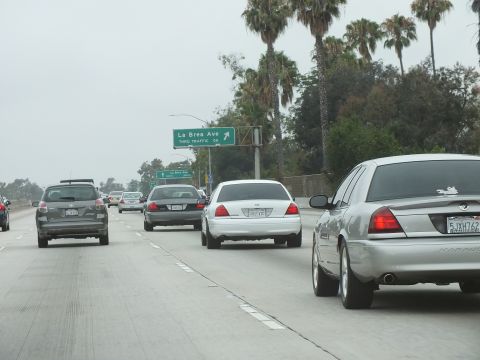 2003 Ford Crown Victoria - Photograph of sedans on a freeway approaching a green La Brea Ave overhead sign and palm trees.