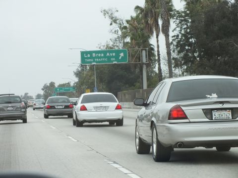 2003 Ford Crown Victoria - Photograph of sedans on a freeway beneath a green La Brea Ave exit sign with palm trees.