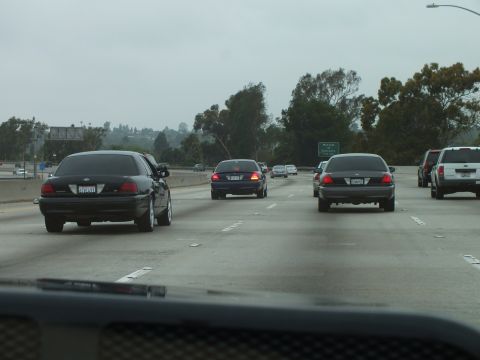 2003 Ford Crown Victoria - Photograph of freeway traffic shot over a dark dashboard on a gray day.
