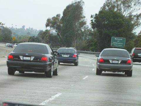 2003 Ford Crown Victoria - Photograph of dark sedans on a freeway near a green Museum of Tolerance exit sign.