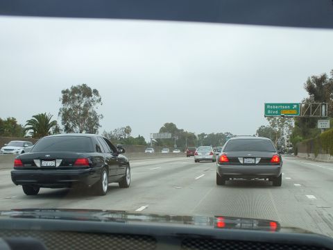2003 Ford Crown Victoria - Photograph of dark sedans on a freeway near a green Robertson Blvd sign, shot through a windshield.