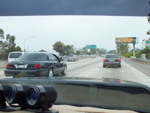 2003 Ford Crown Victoria - Photograph of freeway traffic with an electronic message board, binoculars resting on the dashboard.