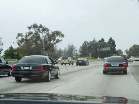 2003 Ford Crown Victoria - Photograph of a black Crown Victoria and other sedans in freeway traffic among trees.