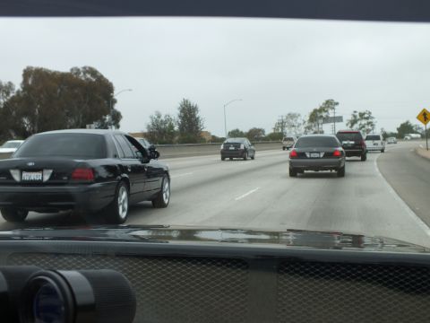 2003 Ford Crown Victoria - Photograph of freeway traffic with a black sedan and binoculars resting on the car dashboard.