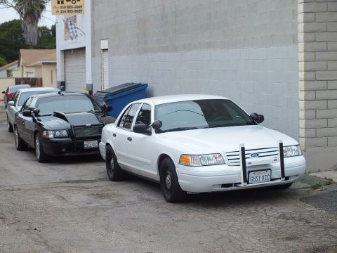 2003 Ford Crown Victoria - Photo of a white Ford Crown Victoria with grille guard parked in an alley next to a black one.