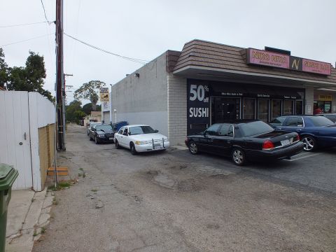2003 Ford Crown Victoria - Photo of Ford Crown Victoria sedans parked along an alley beside a sushi restaurant.