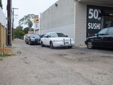 2003 Ford Crown Victoria - Photo of white and black Ford Crown Victoria sedans parked in an alley by a sushi restaurant.