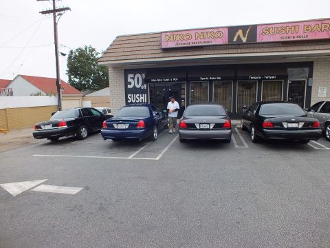 2003 Ford Crown Victoria - Photo of black and blue Ford Crown Victoria sedans parked in front of a sushi restaurant.