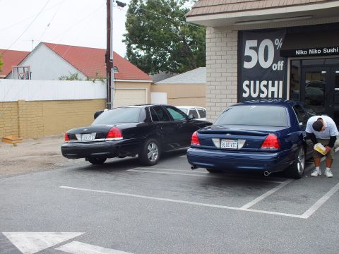 2003 Ford Crown Victoria - Photo of dark Ford Crown Victoria sedans parked outside a sushi restaurant, one with BLUE VIC plate.
