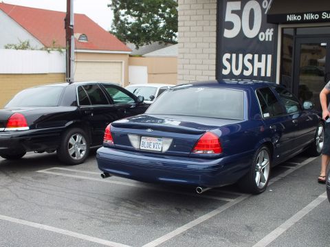 2003 Ford Crown Victoria - Photo of a blue Ford Crown Victoria with BLUE VIC plate parked beside a black one at a sushi bar.
