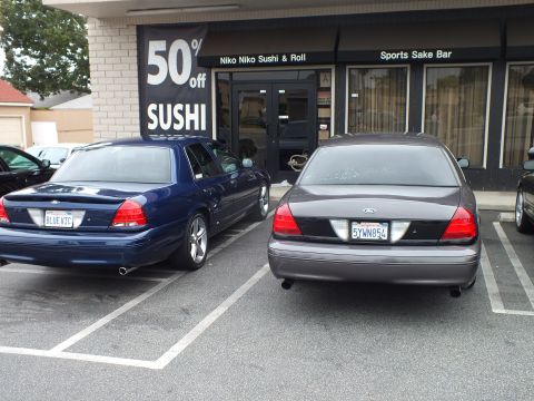 2003 Ford Crown Victoria - Photo of blue and gray Ford Crown Victoria sedans parked outside a sushi restaurant.