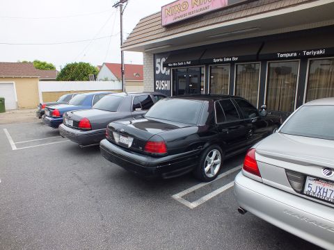 2003 Ford Crown Victoria - Photo of a row of Ford Crown Victoria sedans parked in front of a sushi restaurant.