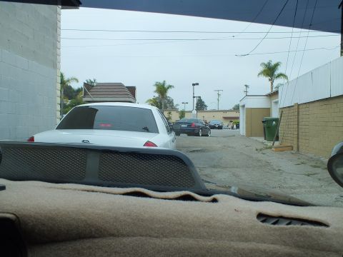 2003 Ford Crown Victoria - Photo taken through a car windshield showing a white Crown Victoria parked in a back alley.