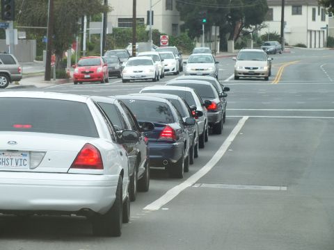 2003 Ford Crown Victoria - Photo of a white Crown Victoria parked at the curb at the head of a line of cars on a city street.