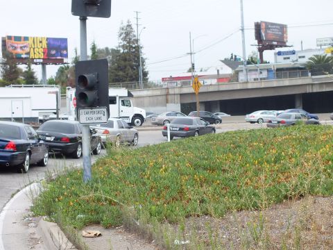 2003 Ford Crown Victoria - Photo of cars at a freeway on-ramp signal as a truck crosses, with a Kick-Ass 2 billboard behind.
