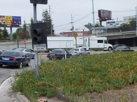 2003 Ford Crown Victoria - Photo of cars and a recreational vehicle at a freeway on-ramp with a flowering median and billboards.